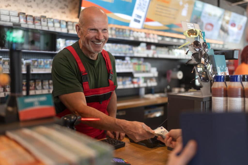 Older employee Employee taking cash payment from costumer in grocery store