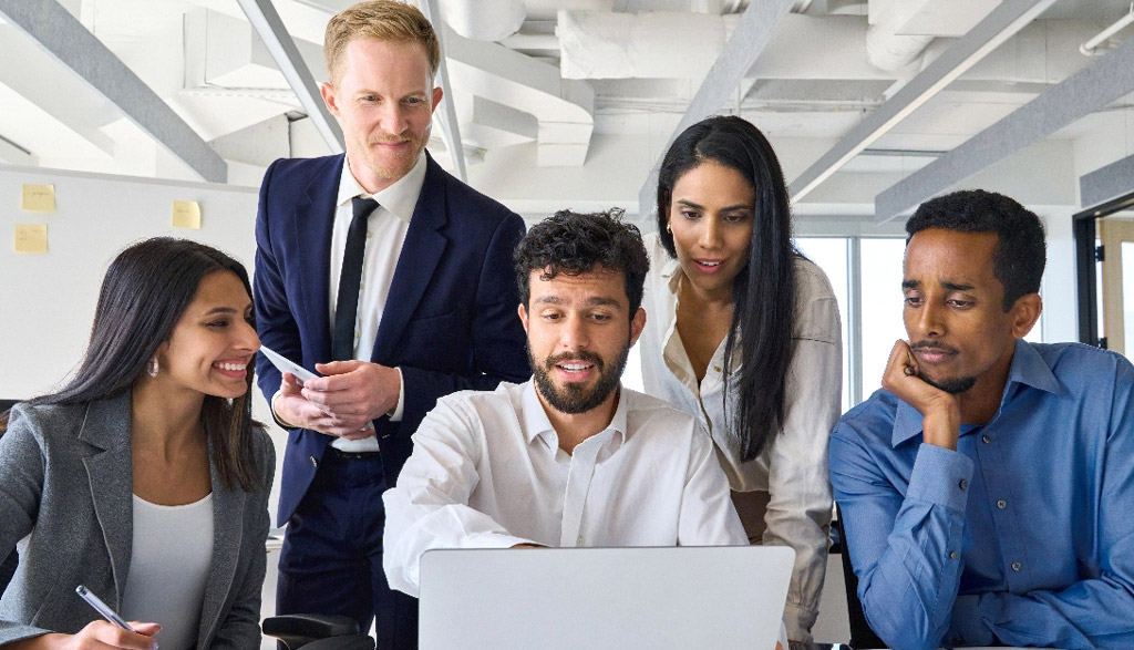 Group of diverse office workers looking at laptop in boardroom mobile