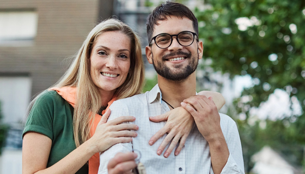 Happy couple holding keys mobile