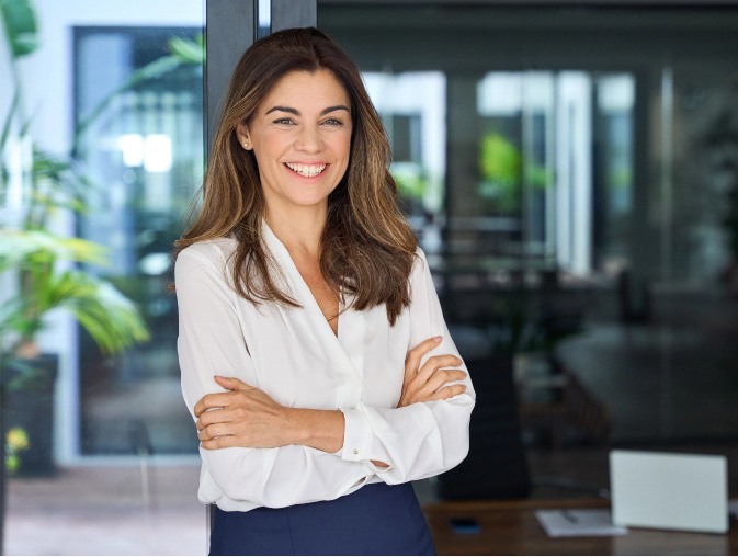 Middle aged business woman smiling with arms folded