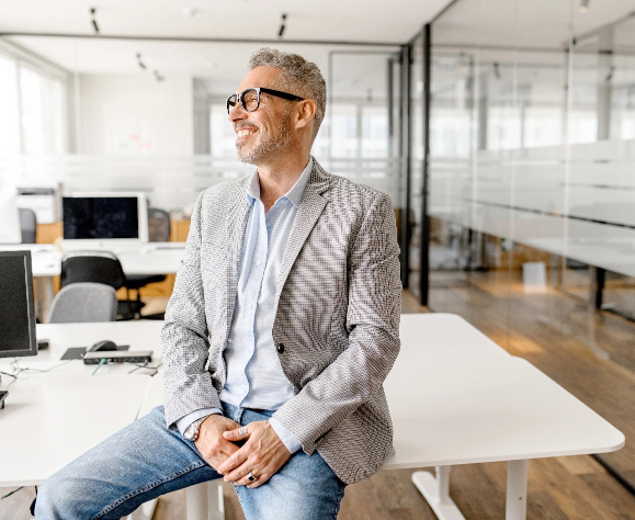 Middle aged casual professional man sitting on desk