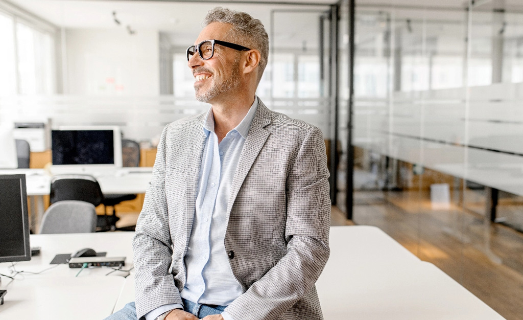 Middle aged casual professional man sitting on desk tablet