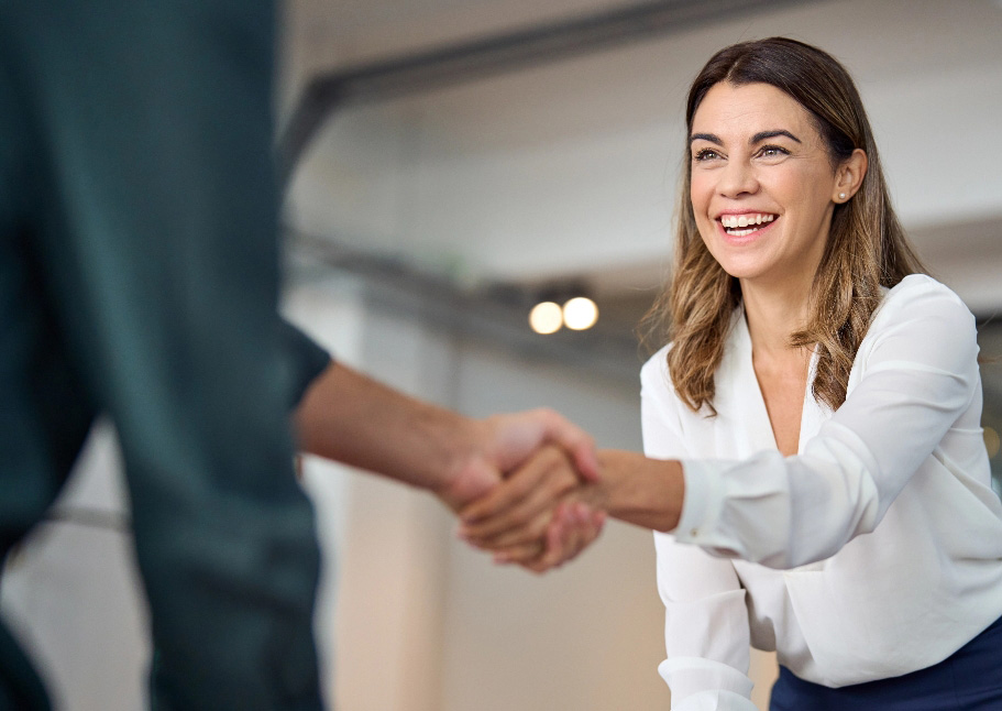 Professional woman smiling, and shaking hands with client