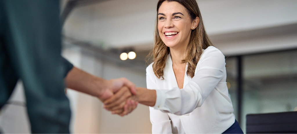 Professional woman smiling, and shaking hands with client