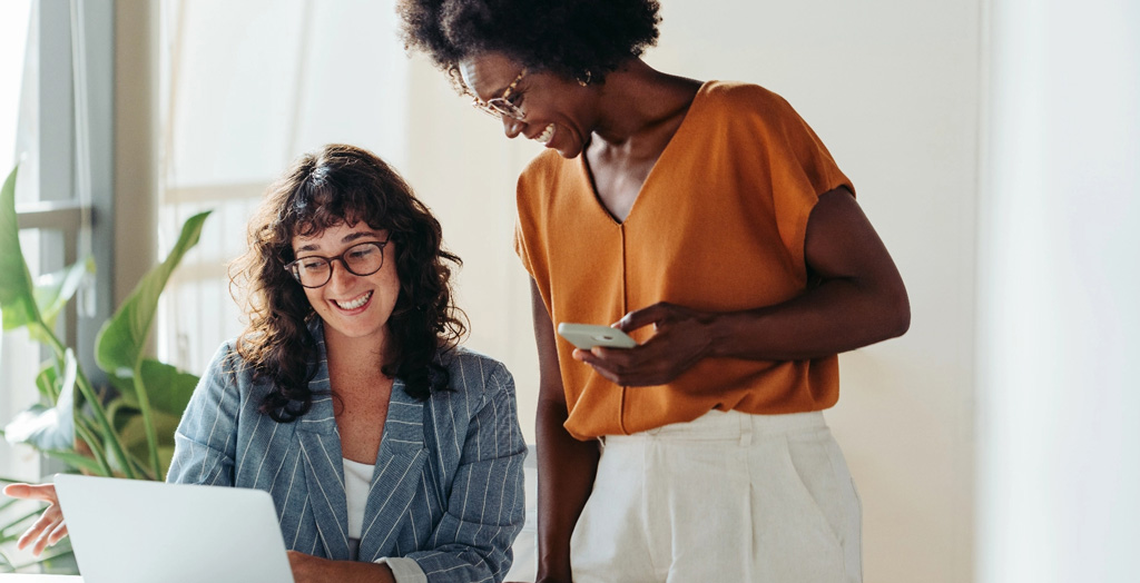 Two business women looking at laptop tablet