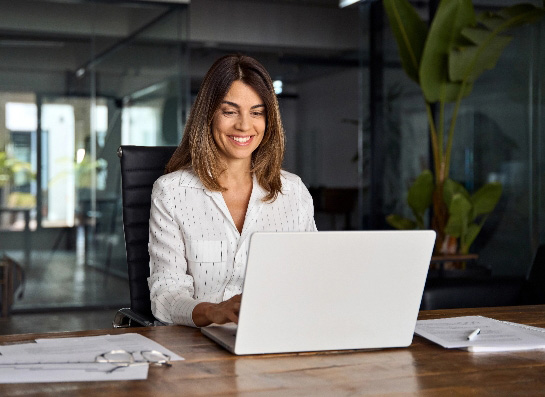 Woman ceo using laptop application for work sitting at table
