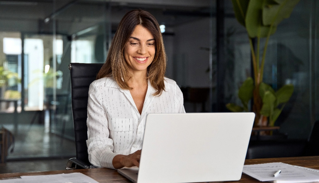 Woman ceo using laptop application for work sitting at table tablet